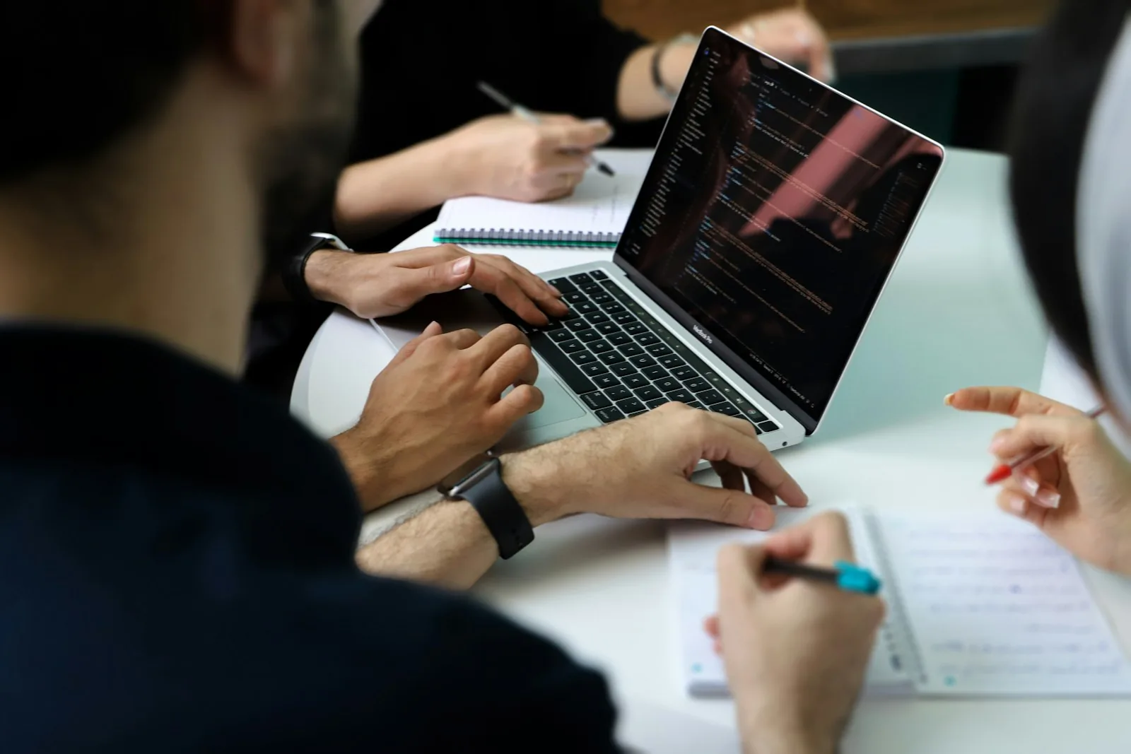 Team trabajando alrededor de una mesa con computadoras y cuadernos